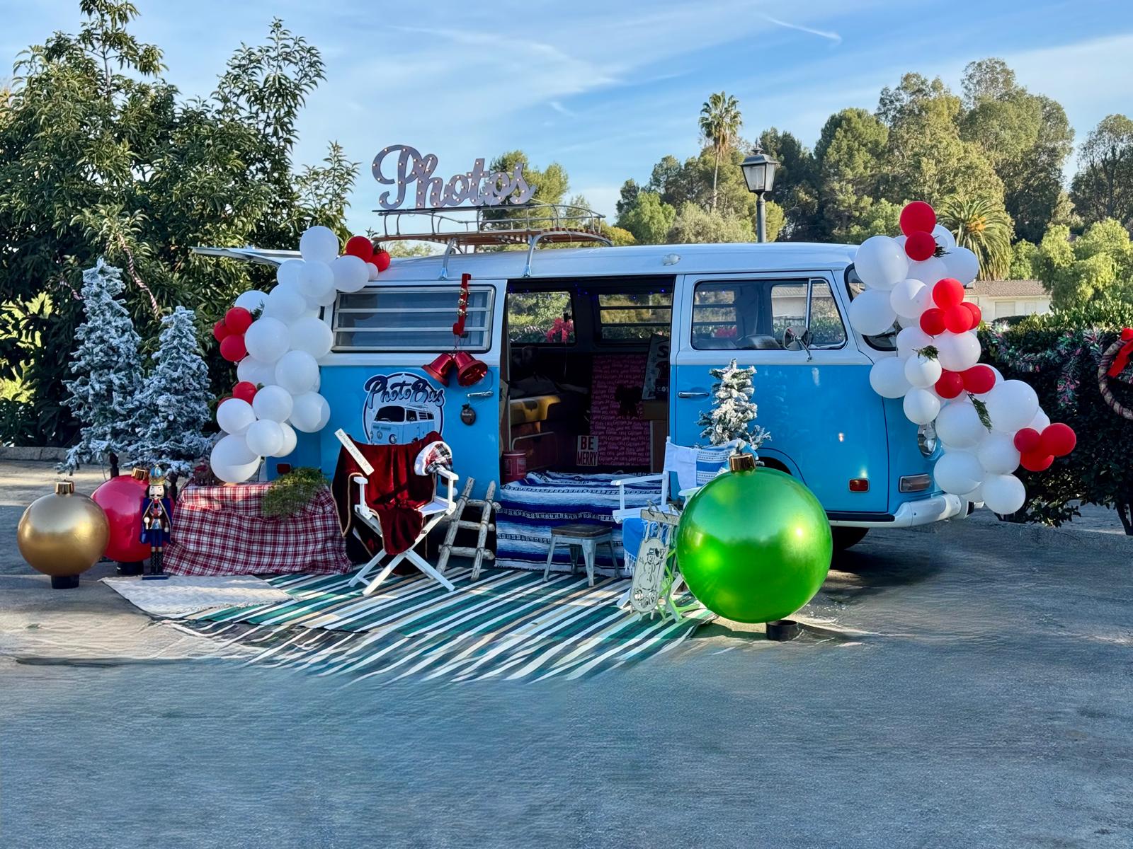 Restored 1970 VW photo bus styled with balloon arches and a lit Photos marquee sign at a Los Angeles event