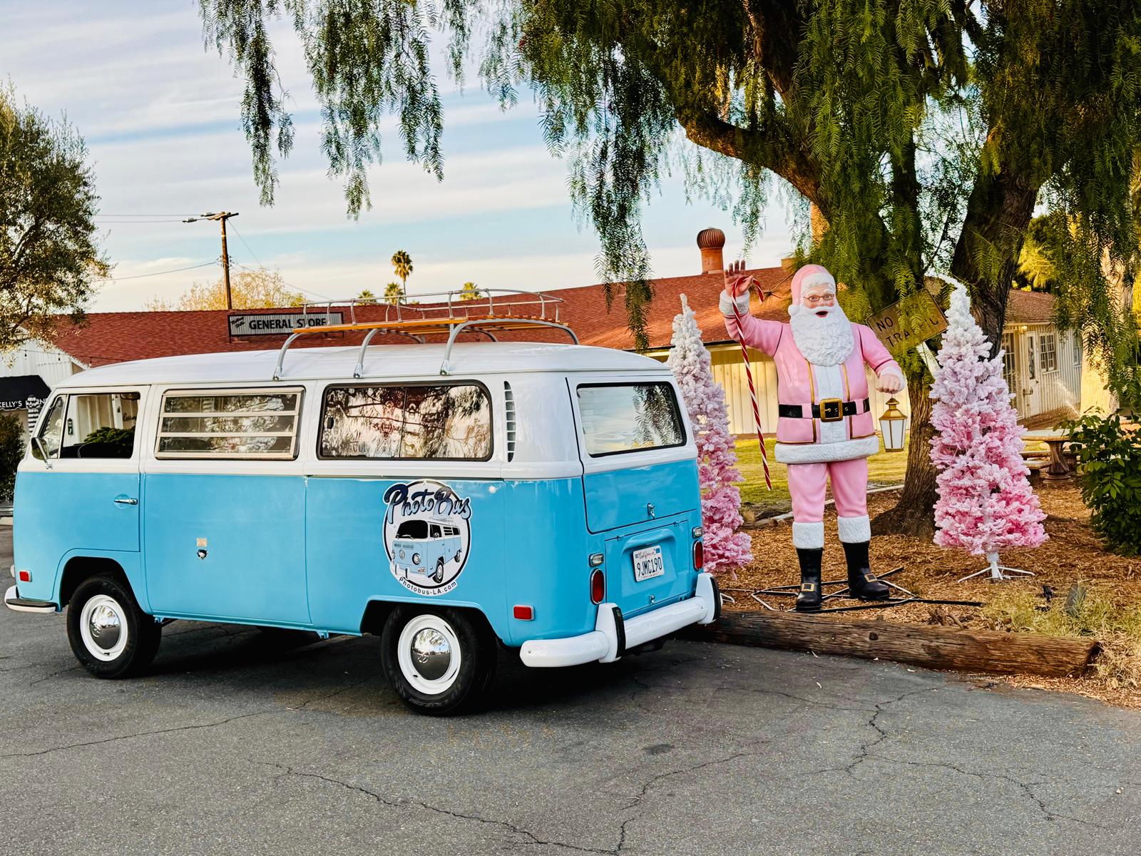 Side profile of the restored sky blue VW Photobus with roof rack parked by a general store at golden hour